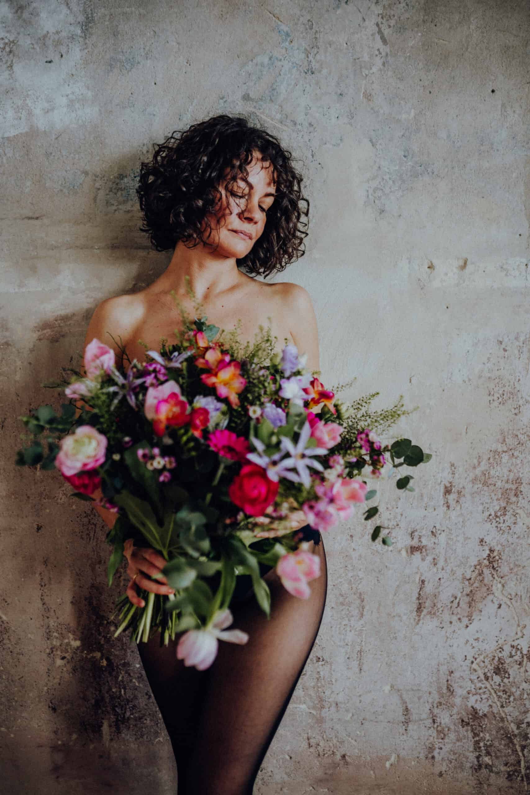 Frau mit freier Schulter und Blumen in der Hand